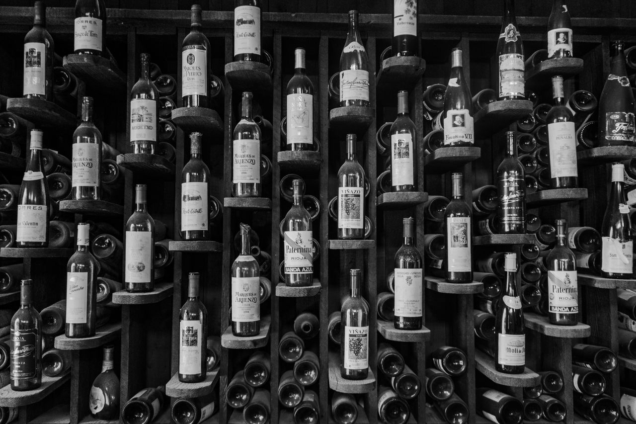 Crafting Captivating Headlines: Your awesome post title goes here A black and white photo showcasing an elegant wine rack filled with various bottles.