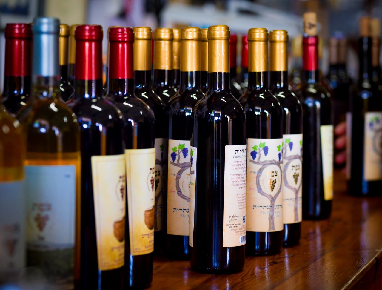 Home Close-up of assorted wine bottles on display at a winery showcasing various labels and colors.